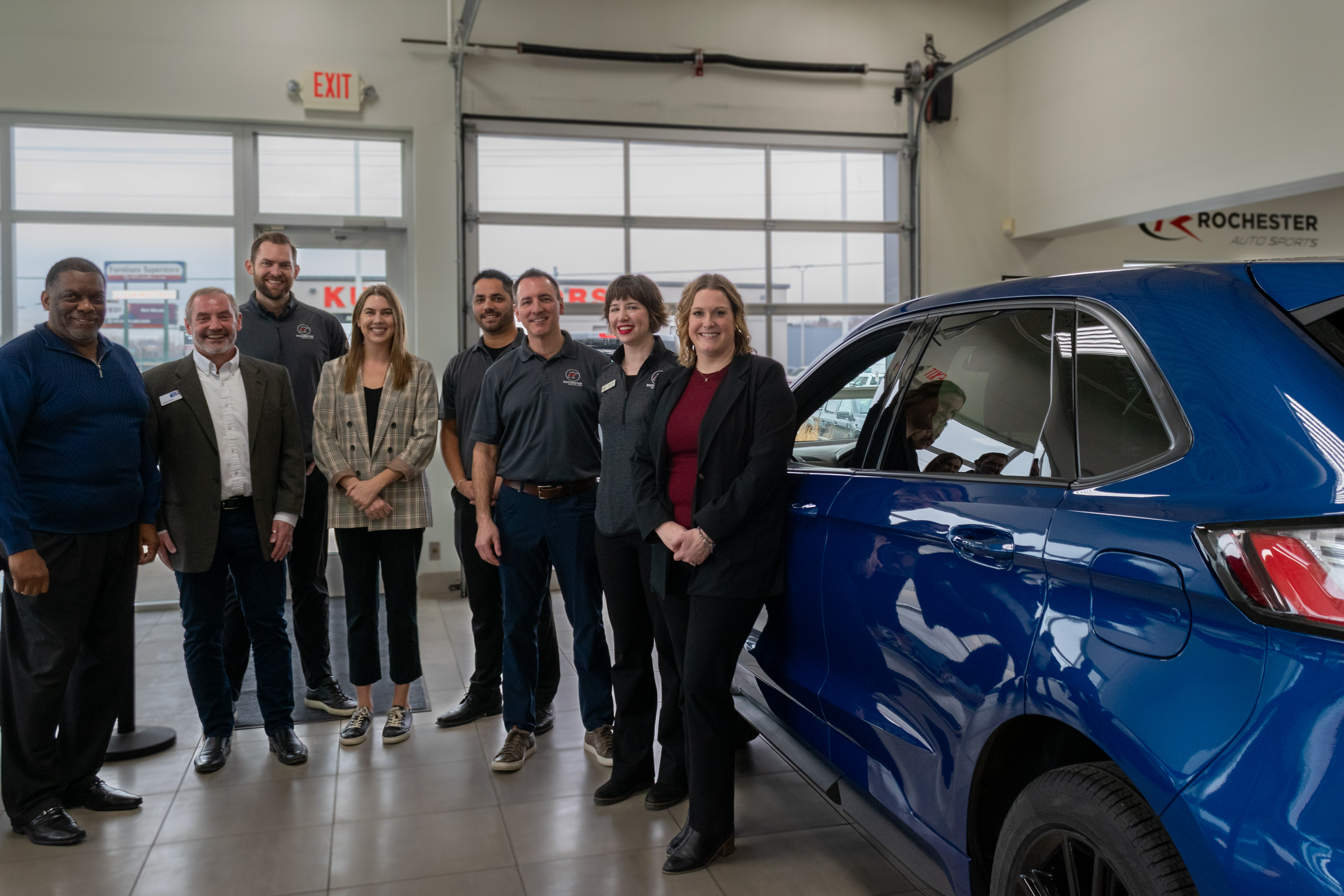 group of white people and one black man beside a blue ford edge