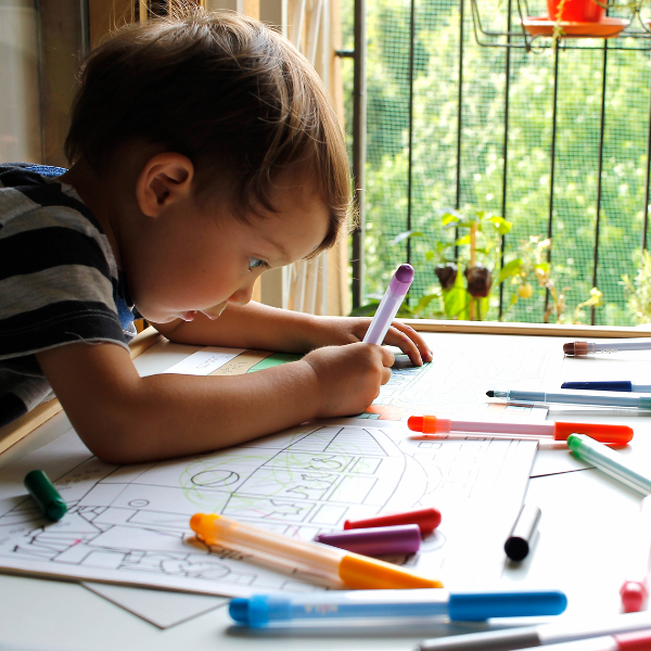 a young boy colors with markers